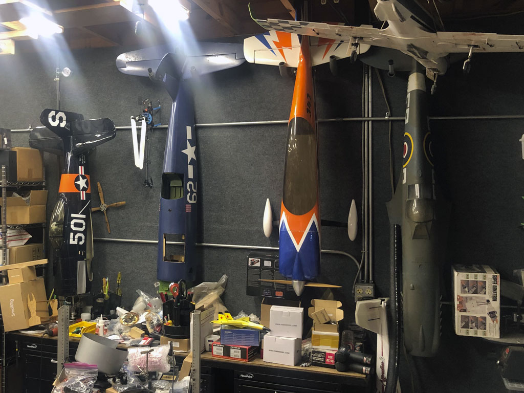 Photo of conveniently storing model airplane fuselages by hnaging on hooks on workshop walls