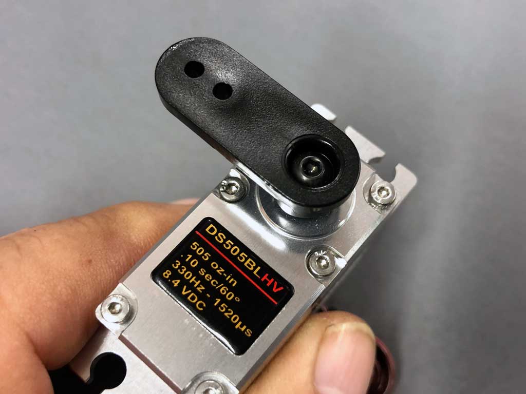 Close up photo of a hand holding ProModeler DS505BLHV, one of the world's best servos with a heavy duty nylon PDRS105 servo arm as used for throttle control