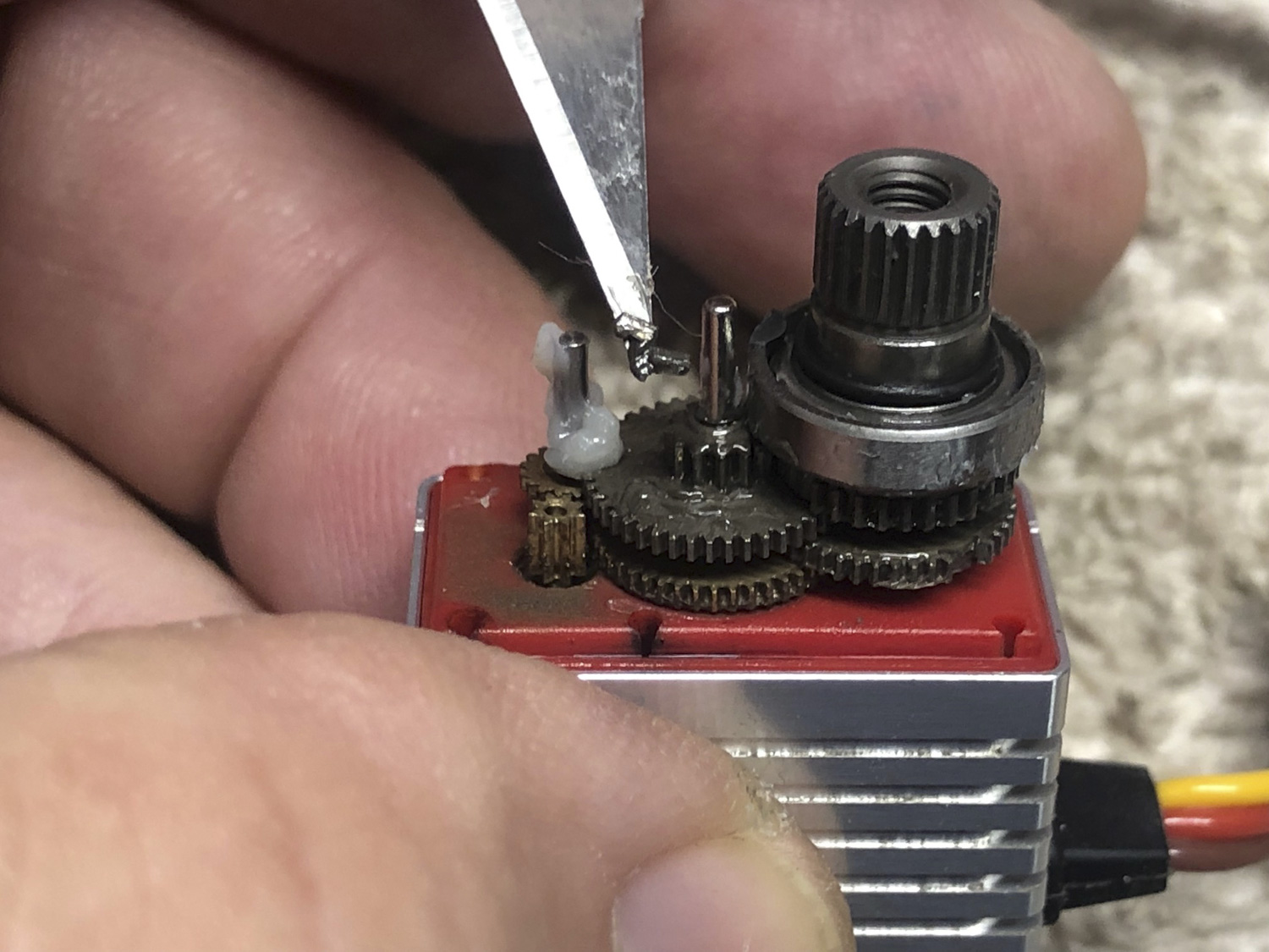 Extreme close up of micr servo gear failure shows the tooth on the tip of an X-Acto #11 blade, which demonstrates the extreme fragility of tiny gear trains when asked to handle too big a job