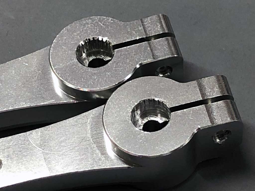 Extreme close up of two alloy servo horns against a neutral gray background showing the damage done to one by an über fast ProModeler DS634BLHV servo.