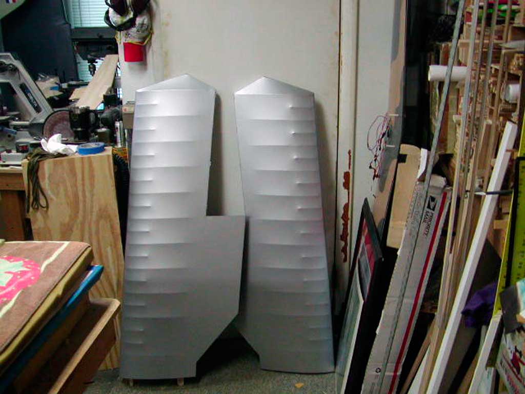 Silver Solartex covered wings for a BUSA Morane-Saulnier lean against the wall of a workshop.