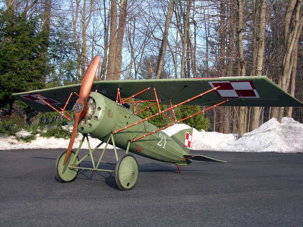 A green model airplane of a WWI Morane-Saulnier on asphalt with snow in the backgroundt with snow in the background.