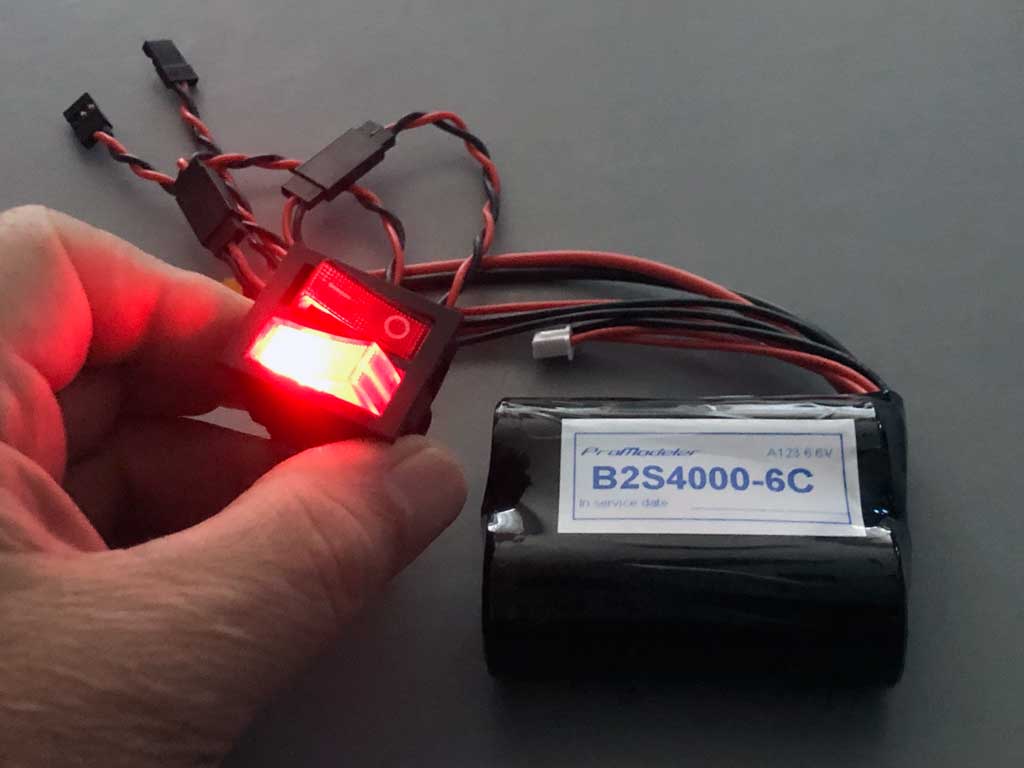 Close up of a hand holding a ProModeler DUAL 20A illuminated rocker switch