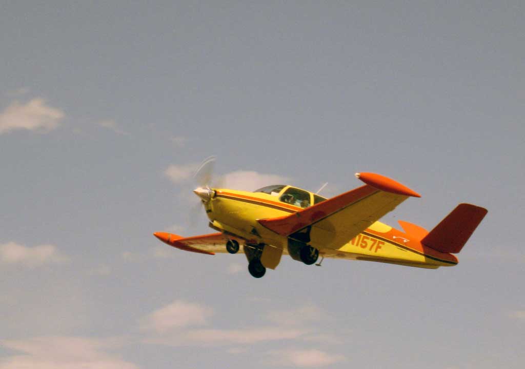 Close up of yellow and orange Beechcraft E-35 Bonanza on deprture