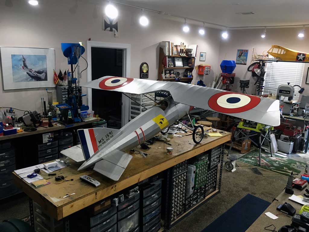 Wide shot of a BUSA Morane-Saulnier A.1 model assembled on a workbench.