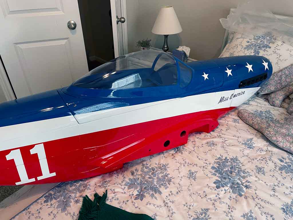Close up of a Miss American fuselage placed on a bed for a sense of scale, the top hatch opening is discrete and blends in nicely.