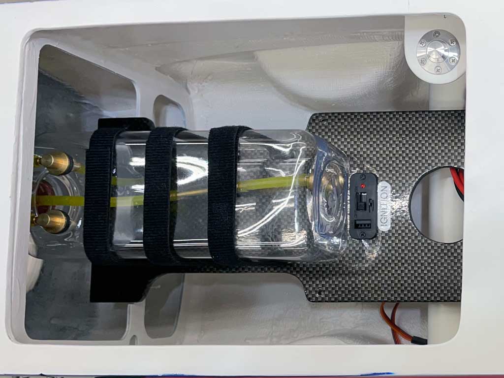 Close up of model airplane fuel tank strapped into place within the fuselage.