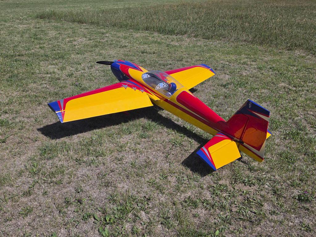 Aft quartering field photo of an Extreme Flight 85-inch Extra 300EXP against a grass background