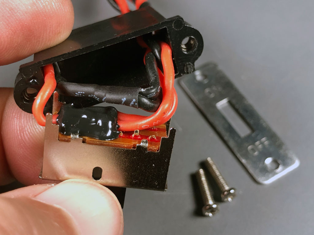 Photo of the reverse side of a ProModeler slide switch reveals metal shielding against stray RFI and potting compound to preotect against vibration