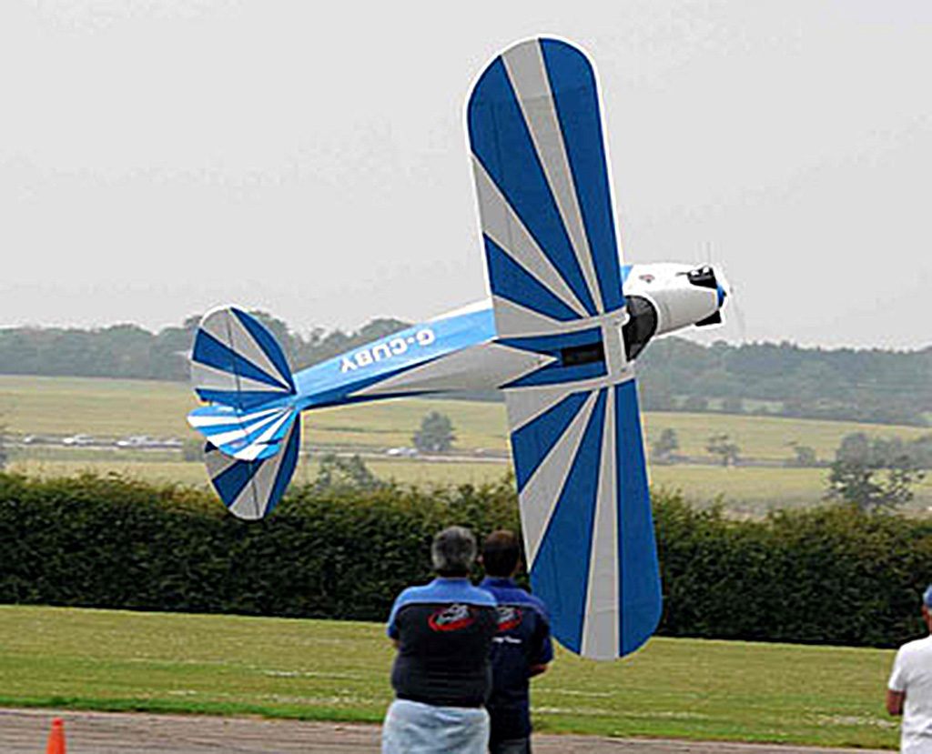 Field photo of Bill Hempel piloting one of his giant scale Cubs in knife edge low to the deck