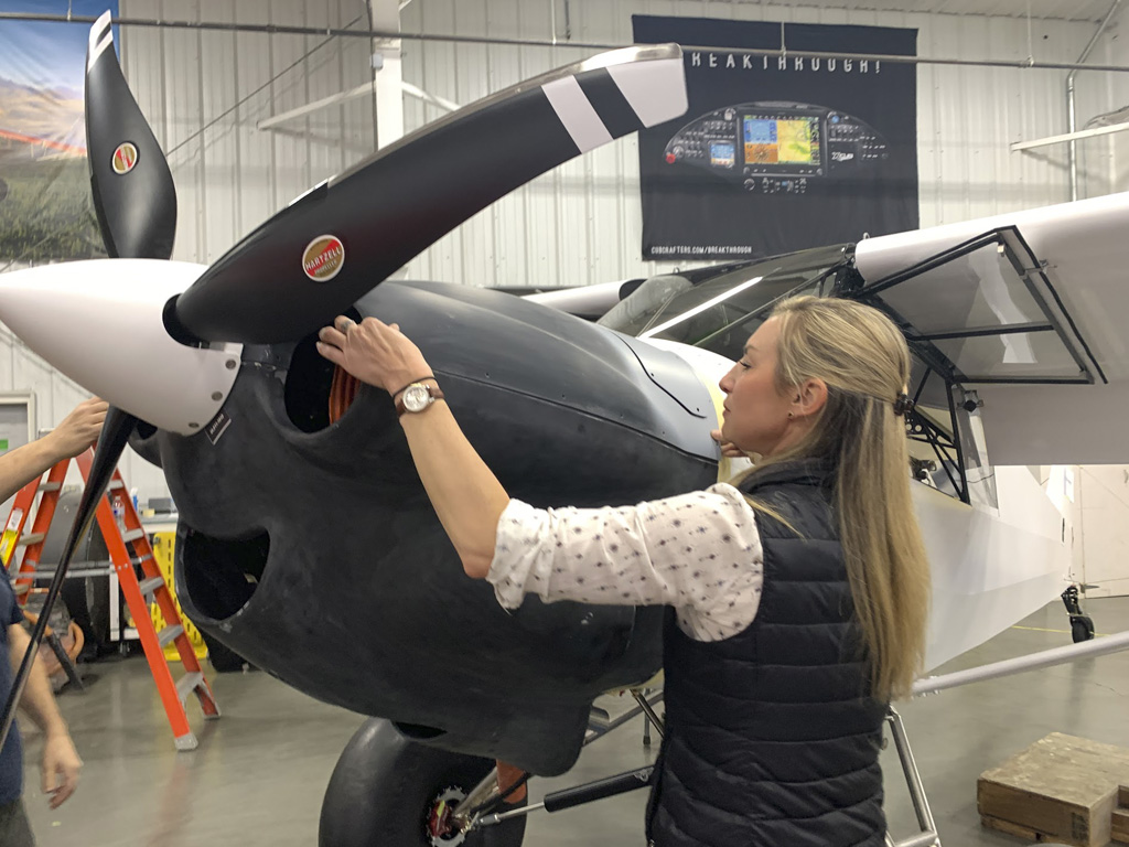 Close up photo of Jackie Burch fitting a carbon fiber cowl to a Cubcrafters Carbun Cub aircraft on the factory floor