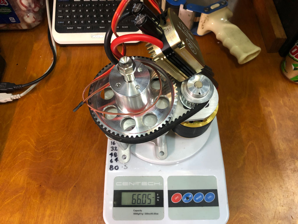 An electric motor with belt-reduction drive sitting on a scale.