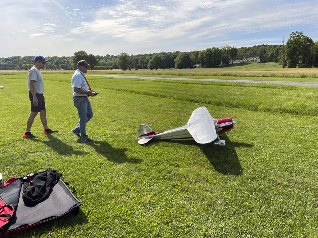 Wide angle photo of Matt and his Cessna 195 taking the active runway at the grass strip of the flying field