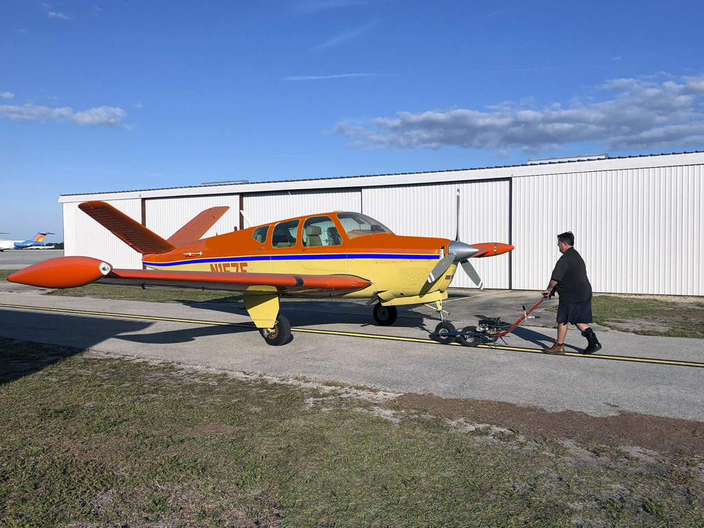 Wide angle photo of John towing N157F back the hangar after being washed