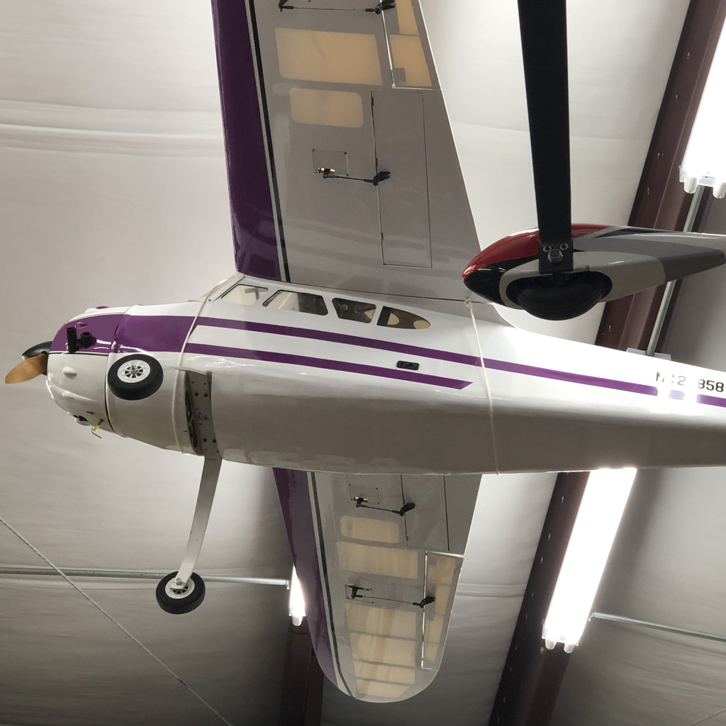 Wide angle photo of quarter scale Cessna 195 by ECOM RC suspended from the ceiling