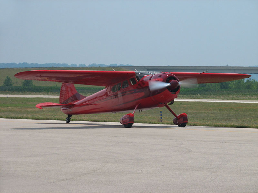 Photo of bright red and maroon trim Cessna 195 taxiing