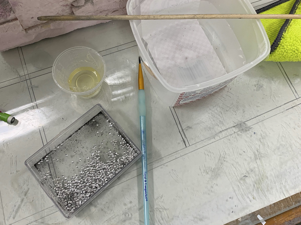 Close up photo of the stabs being detailed and covered in Flite-Metal for a Hostetler quarter scale Cessna 195 model with the bin containing hundreds of real aluminum rivet heads