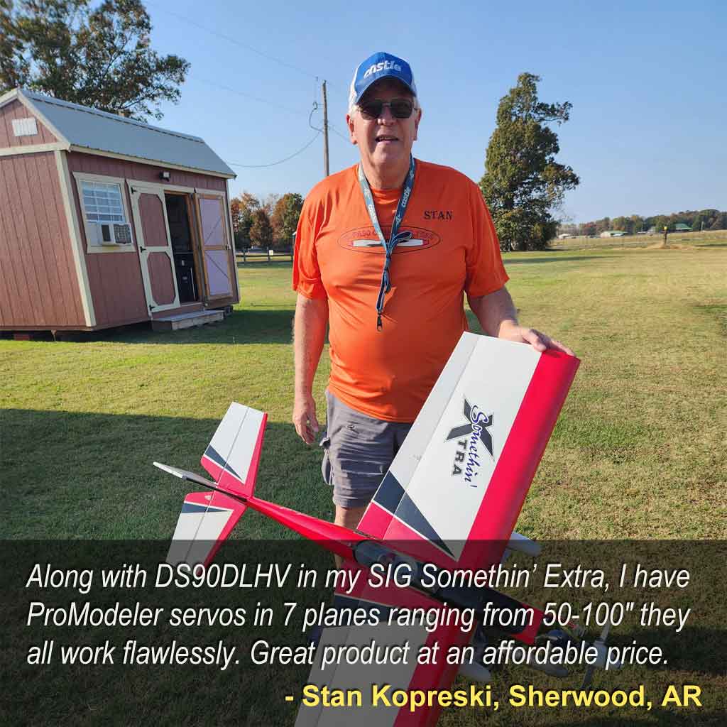 Pilot with red and white SIG Somethin' Extra stand before red shed at a flying field.