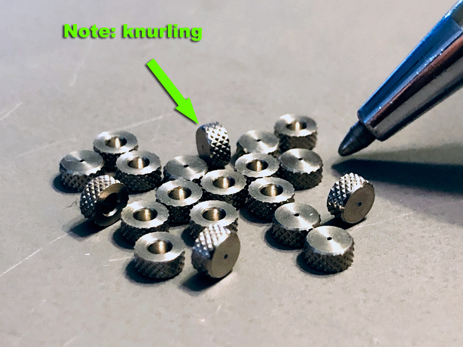 Extreme close up photo of ProModeler inserts with the tip of a Cross gold pen showing the diminutive size of the Swiss turned stainless steel knurled inserts used as hardpoints to reinforce the aluminum alloy servo case